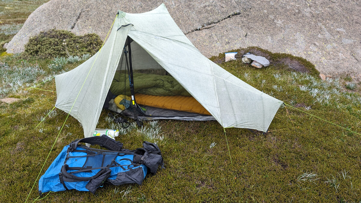 Kampeeruitrusting uitgespreid op gras: tent, slaapzak en rugzak